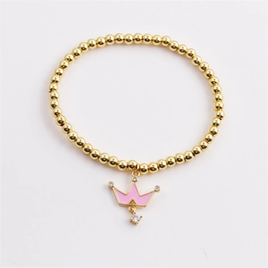 Détail d'un bracelet à perles dorées avec un pendentif couronne en émail rose et zircon