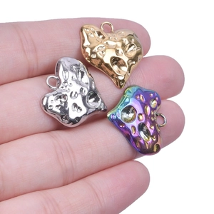 Textured heart pendants in gold, silver and rainbow steel colors held in hand