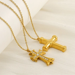 Macro view of gold cross necklaces with crystals on soft beige fabric background