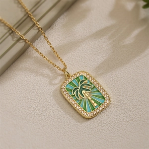Macro shot of gold palm tree tarot pendant with colorful enamel and crystal pavé details