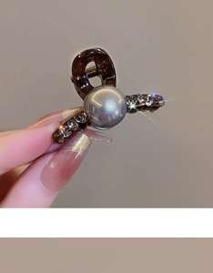 Detail view of a brown pearl hair claw clip with sparkling rhinestones for hair styling