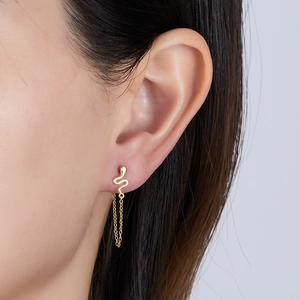 Detailed macro view of a gold-toned snake earring with a delicate dangling chain tassel.