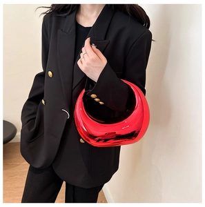 Fashionable red acrylic crescent handbag with a mirror finish held by a model in a blazer
