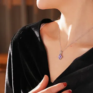 Collier trèfle en argent avec zircons violets porté sur un vêtement en velours