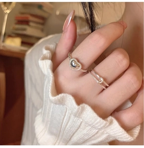 Detail of silver heart ring and twisted band worn on hand with pleated sleeve