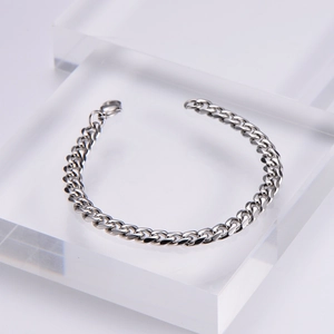 Macro detail of high-polished silver cuban chain bracelet with secure lobster clasp closure