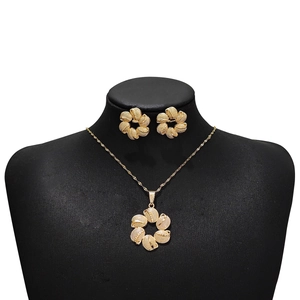 Golden flower jewelry set with necklace and earrings displayed on a black mannequin bust