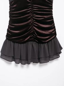 Dettaglio di abito in velluto marrone scuro con arricciatura e orlo in chiffon doppio