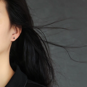 Close-up of minimalist square black zircon stud earrings worn by a female model
