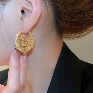 Detail of layered 18k gold plated chain hoop earrings worn by a model in black suit