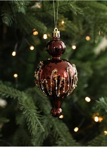 Macro view of burgundy teardrop ornament with glitter waves on a Christmas tree