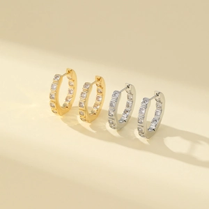 Close-up of geometric gold and silver hoop earrings with clear cubic zirconia inlays