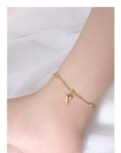 Detail of 18k gold plated titanium anklet with heart pendant and sparkling zircons