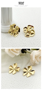 Detail of gold flower earrings with polished finish and petal texture on white stone