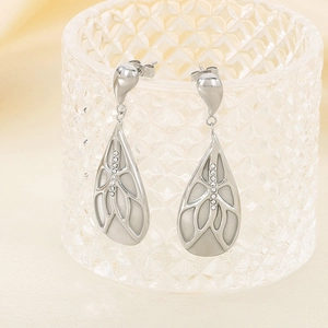 Macro shot of silver drop earrings with hollow design and inlaid rhinestones on glass