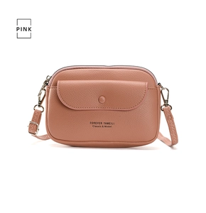 Close-up of pink pebbled leather crossbody bag featuring a front pocket and zipper closure