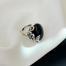Vista macro dell'anello in argento S925 con pietra nera e dettagli floreali su seta bianca