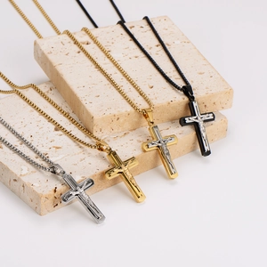 Cross pendant necklaces in silver, gold, and black displayed on natural stone