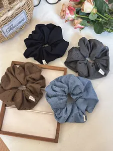 Detail of four fabric hair scrunchies in muted colors with Hand Made label