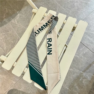Dettaglio di un foulard per capelli in seta pied de poule verde con stampa a lettere
