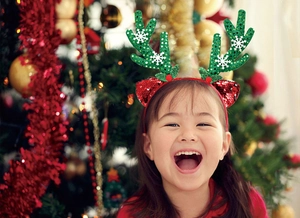 Close-up of green sequin reindeer antlers with white snowflakes and a red festive bow