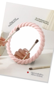 Detail of a pink cream-style vanity mirror with twisted frame on a white tabletop