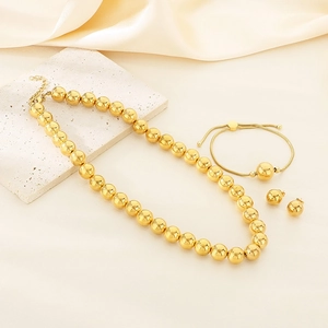 Detailed view of golden bead necklace, bracelet, and earrings set on beige silk