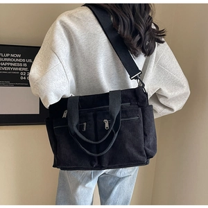 Detail of black corduroy crossbody bag with multiple front pockets and adjustable strap