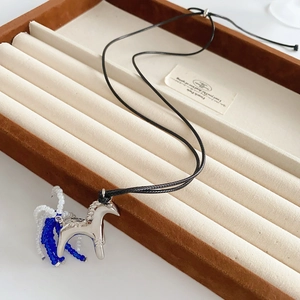 Detail of silver unicorn pendant with blue and white beads on black cord in a brown box