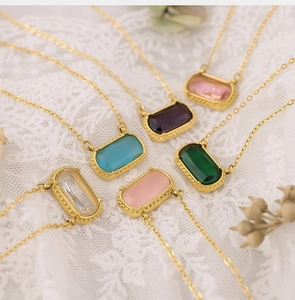 Detailed display of six gold necklaces with colorful rectangular zircon stones on lace