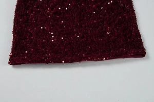 Macro shot of burgundy sequin fabric texture with velvet base and hemline detail