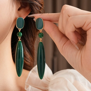 Detailed close-up of vintage malachite drop earrings with silver needle on model