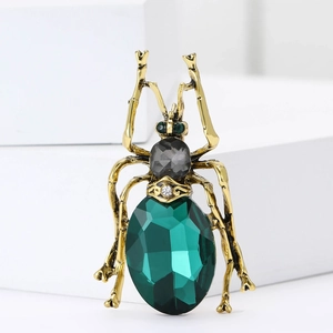 Vintage gold insect brooch with large green faceted gemstone and detailed legs