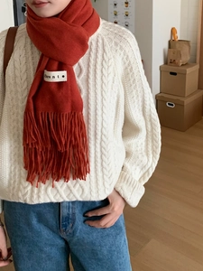 Detailed close-up of a red cashmere-feel scarf with fringes and a woven label detail