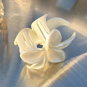 Macro detail of pearlescent lily flower hair claw clip with glossy finish and elegant texture