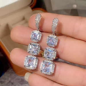 Macro detail of silver drop earrings featuring triple square-cut cubic zirconia crystals