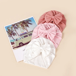 Detailed texture of ribbed elastic baby turbans with large bows in white and pink