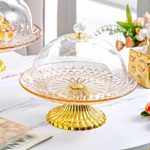 Detail of European cake stand with transparent glass lid and golden metal base texture