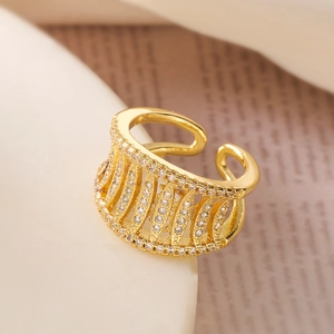 Detail of gold-plated open ring with pavé-set cubic zirconia on a minimalist white stand