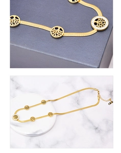Macro detail of gold tree of life pendant with crystals and flat snake chain