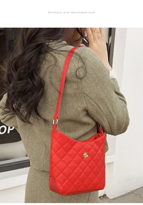 Detail of red quilted shoulder bag with gold floral accent on female model profile