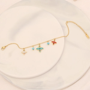 Elegant gold stainless steel bracelet with colorful floral charms and blue beads on marble