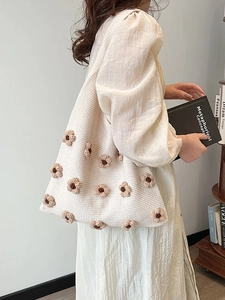 Chic cream knitted tote bag featuring 3D brown floral accents and flexible shoulder straps