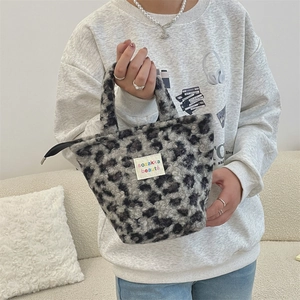 Detail of leopard print plush handbag with soft fuzzy texture and woven brand label