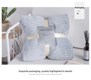 Close-up of folded light blue corduroy blanket with gift ribbon and sleeve packaging