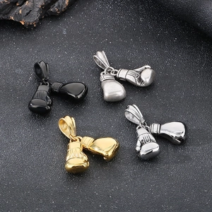Boxing glove pendants in black, gold and silver finish stainless steel on textured surface