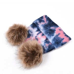 Détail du bonnet en tricot tie-dye avec deux pompons en fausse fourrure marron