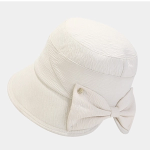 Chic beige sun hat with a large bow and gold buckle detail from a 45-degree angle
