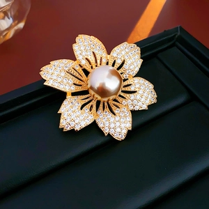 Detail of flower brooch with champagne pearl and white cubic zirconia on gold plating