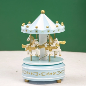 Detail of blue and white carousel music box with golden accents and four horses